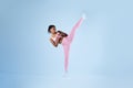 Determined black woman in sportswear doing high kick, tae-bo martial arts exercises on blue background, free space Royalty Free Stock Photo