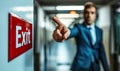 Determined businessman pointing towards an exit sign in a corridor, symbolizing decision-making, direction, departure, and Royalty Free Stock Photo