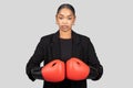 Determined businesswoman in a black blazer with boxing gloves on, ready to face challenges Royalty Free Stock Photo