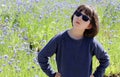 Determined child with blue sunglasses over beautiful floral meadow, outdoor