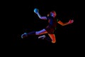 Determined female athlete practicing handball moves with concentration and dedication against black background in neon Royalty Free Stock Photo