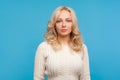 Determined focused beautiful blond girl in white knitted sweater seriously looking at camera, responsibilities