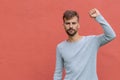 Fist of guy arm raising up showing power strong. Hand over red wall with copy space. Protest concept