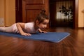 Determined little girl doing push ups, four limbed staff exercise, staying in plank on mat while exrercising indoors