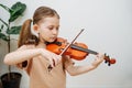 Determined little girl learning to play violin, focusing on her fingers pressing