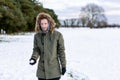 A determined looking young man with a snowball in hand ready to throw it during a snowball fight. He is in a snow covered wintery