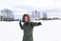 A determined looking young man with a snowball in hand ready to throw it during a snowball fight. He is in a snow covered wintery