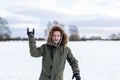 A determined looking young man with a snowball in hand ready to throw it during a snowball fight. He is in a snow covered wintery