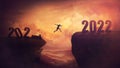 Determined man jump over a chasm obstacle to reach the new 2022 peak and let 2021 behind. Conceptual and surreal sunset scene, new Royalty Free Stock Photo