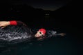 A determined professional triathlete undergoes rigorous night time training in cold waters, showcasing dedication and Royalty Free Stock Photo