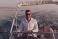 A determined senior businessman in casual clothes and sunglasses enjoys his vacation driving a luxury boat at sunset Royalty Free Stock Photo