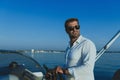 A determined senior businessman in casual clothes and sunglasses enjoys his vacation driving a luxury boat at sunset Royalty Free Stock Photo