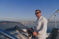 A determined senior businessman in casual clothes and sunglasses enjoys his vacation driving a luxury boat at sunset Royalty Free Stock Photo