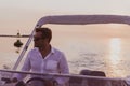 A determined senior businessman in casual clothes and sunglasses enjoys his vacation driving a luxury boat at sunset Royalty Free Stock Photo