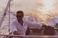 A determined senior businessman in casual clothes and sunglasses enjoys his vacation driving a luxury boat at sunset Royalty Free Stock Photo