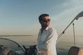 A determined senior businessman in casual clothes and sunglasses enjoys his vacation driving a luxury boat at sunset Royalty Free Stock Photo