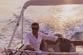 A determined senior businessman in casual clothes and sunglasses enjoys his vacation driving a luxury boat at sunset Royalty Free Stock Photo
