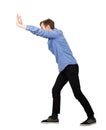 Determined teenage guy making effort as pushing an heavy invisible object isolated on white background. Confident boy, difficult