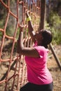Determined woman climbing a net during obstacle course
