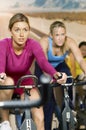 Determined Women Exercising On Bikes In Club