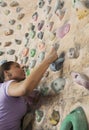 Determined young woman climbing up a climbing wall in an indoor climbing gym Royalty Free Stock Photo