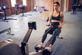 Determined young woman working out on row machine in fitness studio Royalty Free Stock Photo