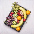 Detox and diet food concept, fresh fruit, bananas, grapes, kiwi and tangerine, strawberry lined vintage wooden box top view Royalty Free Stock Photo