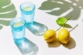 Detox lemon water in blue glasses with fresh lemons, sunlight and shadows Royalty Free Stock Photo