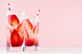 Detox mineral water with ripe strawberry, ice cubes and straw on white wood table and pink background. Royalty Free Stock Photo