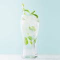 Detox mint drink with green leaves, ice cubes, sparkling water, striped straw in misted glass in modern mint color interior. Royalty Free Stock Photo