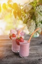 Detox smoothies-banana with strawberry on a background of a bouquet of wild cherry a Sunny evening. The vertical frame.