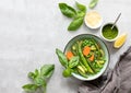 Detox vegetable spring soup, green minestrone inspired recipe, overhead view on ready to eat served with pesto and parmesan dish