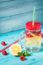 Detox water cocktail with lemon, raspberry and mint, blue wooden background