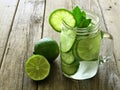 Detox water with lime and cucumbers on wood background Royalty Free Stock Photo