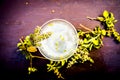 Detoxifying white ice tea in a transparent glass cup on wooden surface.