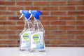 Dettol multi usages antibacterial surface cleaner on white glass table against blurred brick wall background.