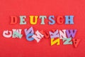 DEUTSCH word on red background composed from colorful abc alphabet block wooden letters, copy space for ad text Royalty Free Stock Photo