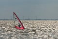 a sailboarder sailing on the rough ocean with wind turbines in the background Royalty Free Stock Photo