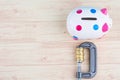 Piggy bank and coins squeezed tightly in a G-Clamp over wooden background Royalty Free Stock Photo