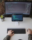Developer is coding using screen and tablet. Freelancer is working from home Royalty Free Stock Photo