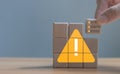 Developer programmer holding a wooden cube with warning triangle sign for notifying error found error and maintenance concept