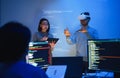 developer uses a VR headset to interact with projected interface designs, while colleagues discuss and code on screens,