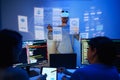 developer uses a VR headset to interact with projected interface designs, while colleagues discuss and code on screens at office