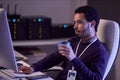 IT developer working at night writing code and drinking coffee at desk in office