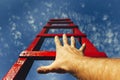 Development Motivation Career Growth Concept. Mans Hand Reaching For Red Ladder Leading To A Blue Sky Royalty Free Stock Photo