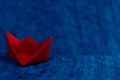 A deviating red paper boat down the high tide in ocean made with blue paper Royalty Free Stock Photo