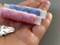 Device for drawing the thread into the eye of the needle. Bobbins with blue and pink threads in the background. A woman Royalty Free Stock Photo