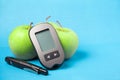 A device that measures glucose in the blood. Glaucometer with green apples
