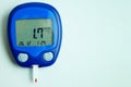 A device for measuring blood sugar with a very low reading (hypoglycemia) on a gray-blue background. Copy space.