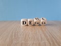 Devil in the details symbol. Turned cubes and changed the word details to devil. Beautiful blue background. Wooden table. Business